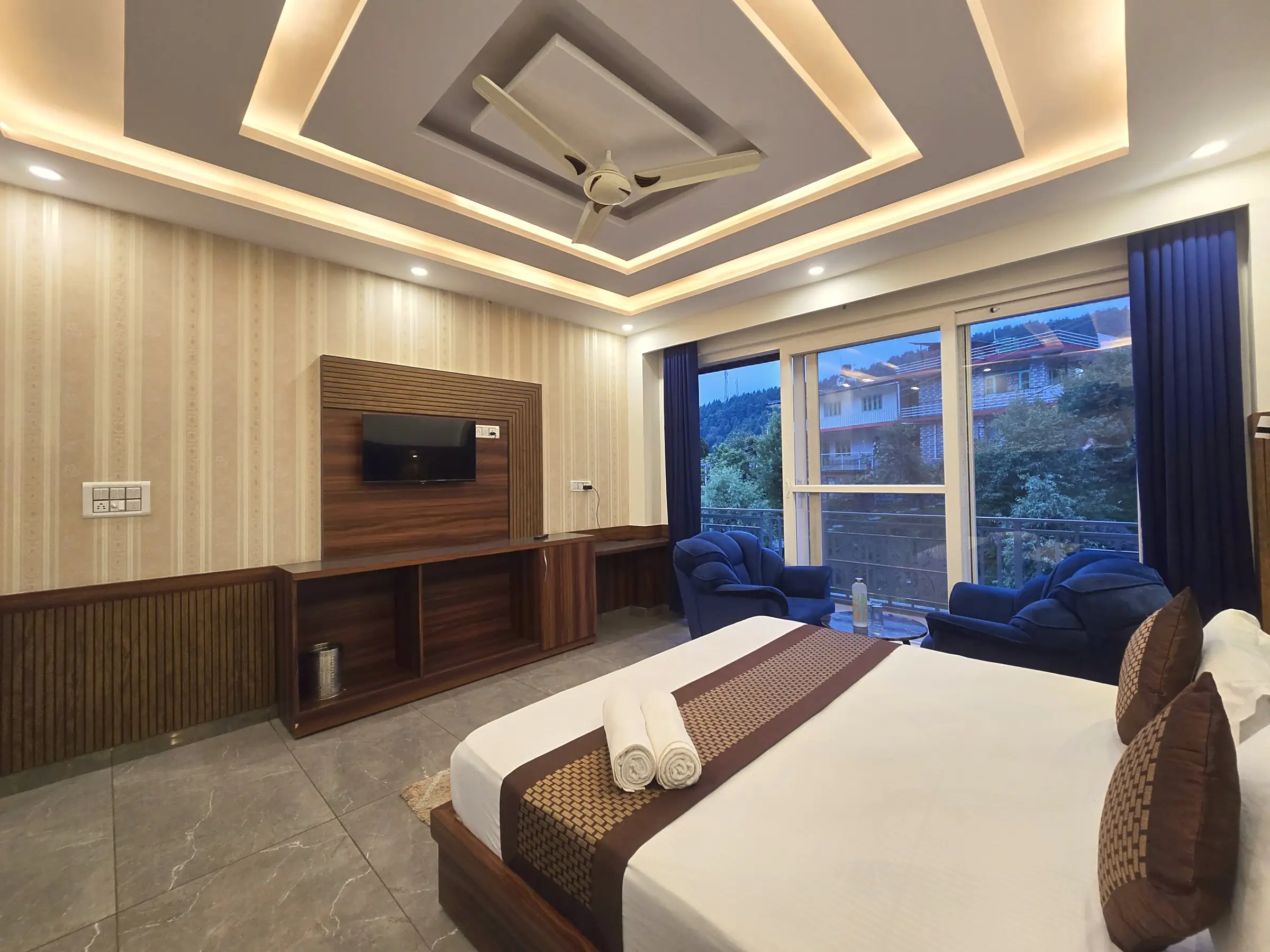 The bedroom, with a double bed, two blue armchairs and a large window