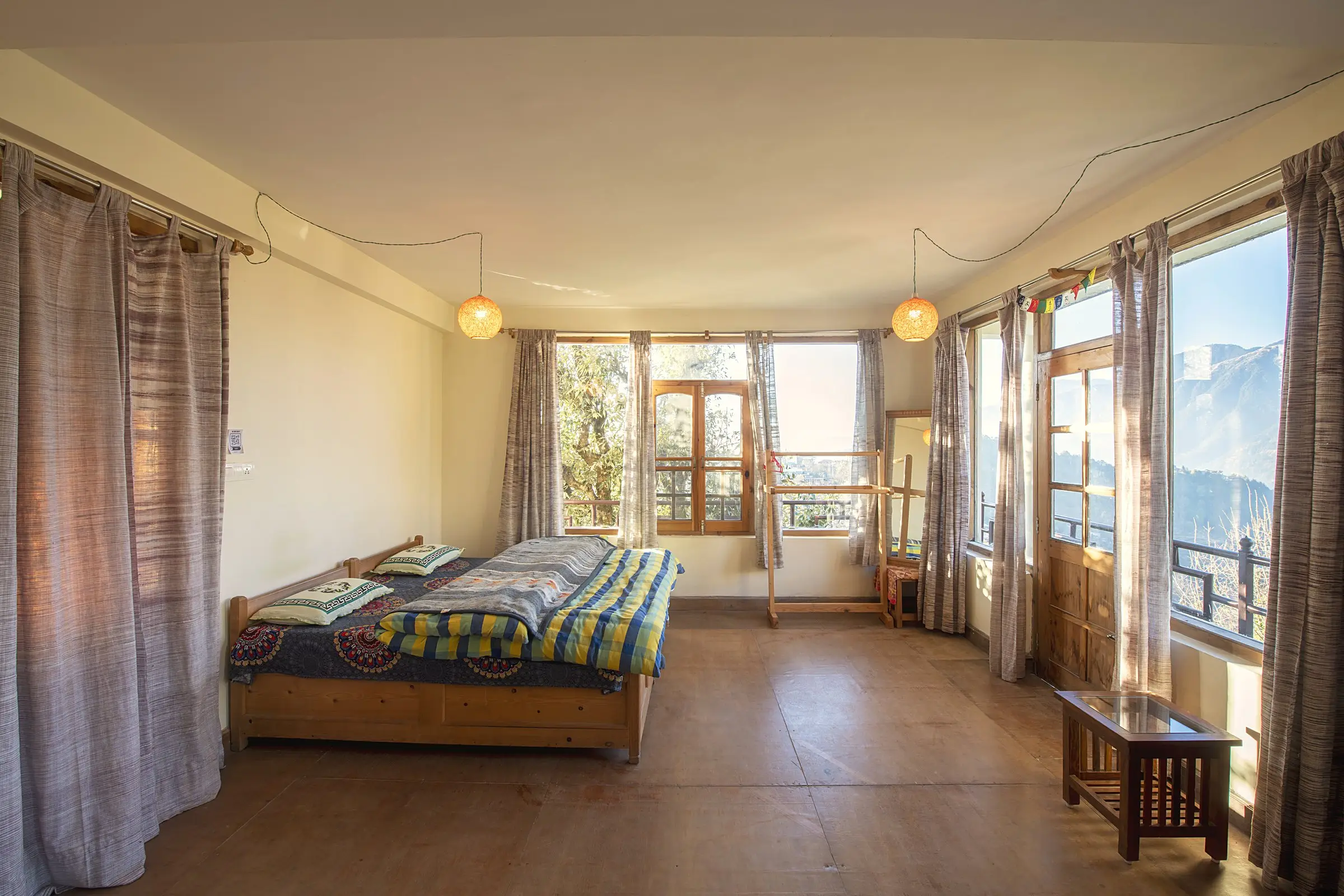 A wide room with a wooden bed, and windows showing snow on the hills