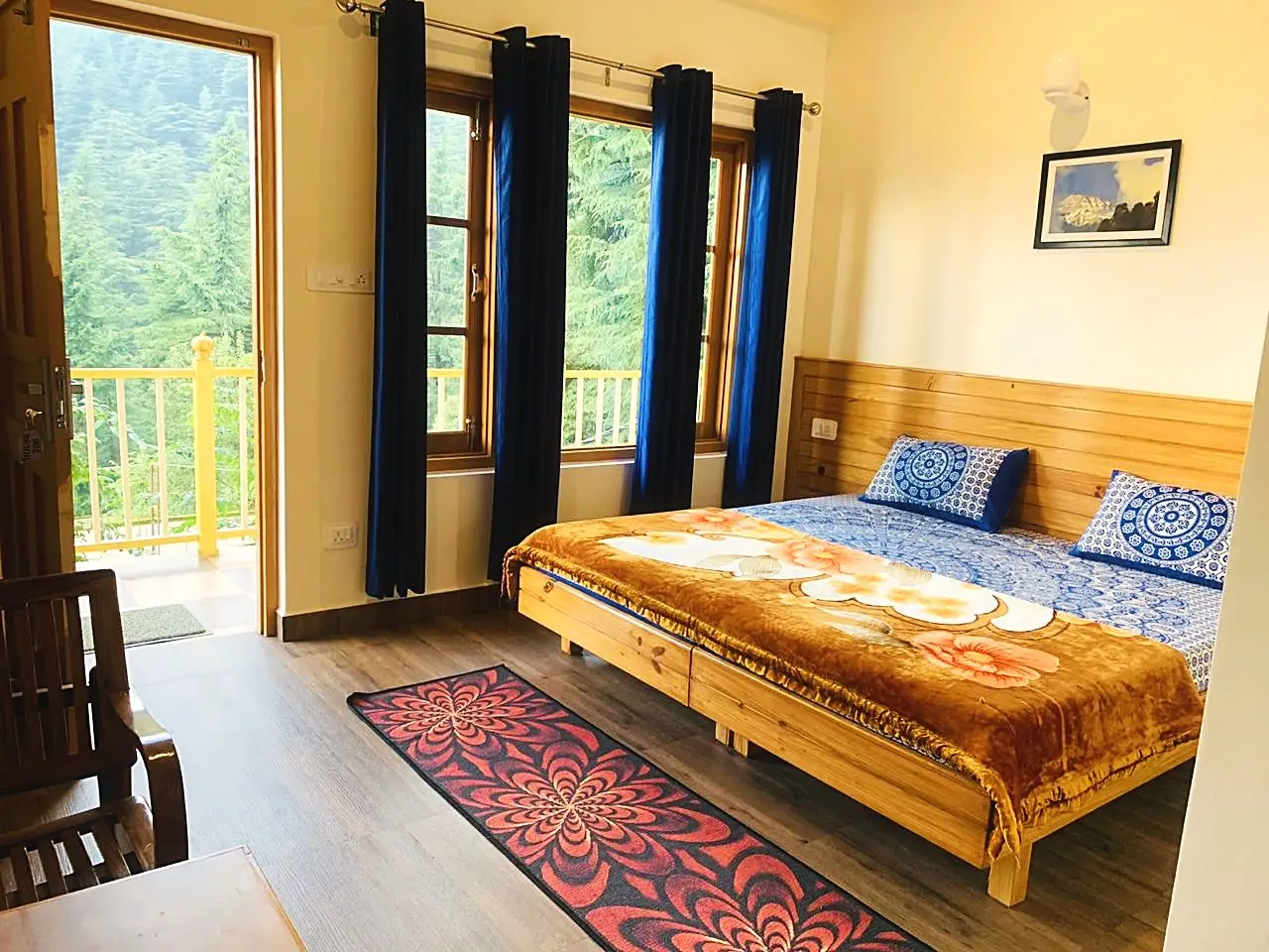 The bedroom, with a double bed, blue curtains and a balcony door open
