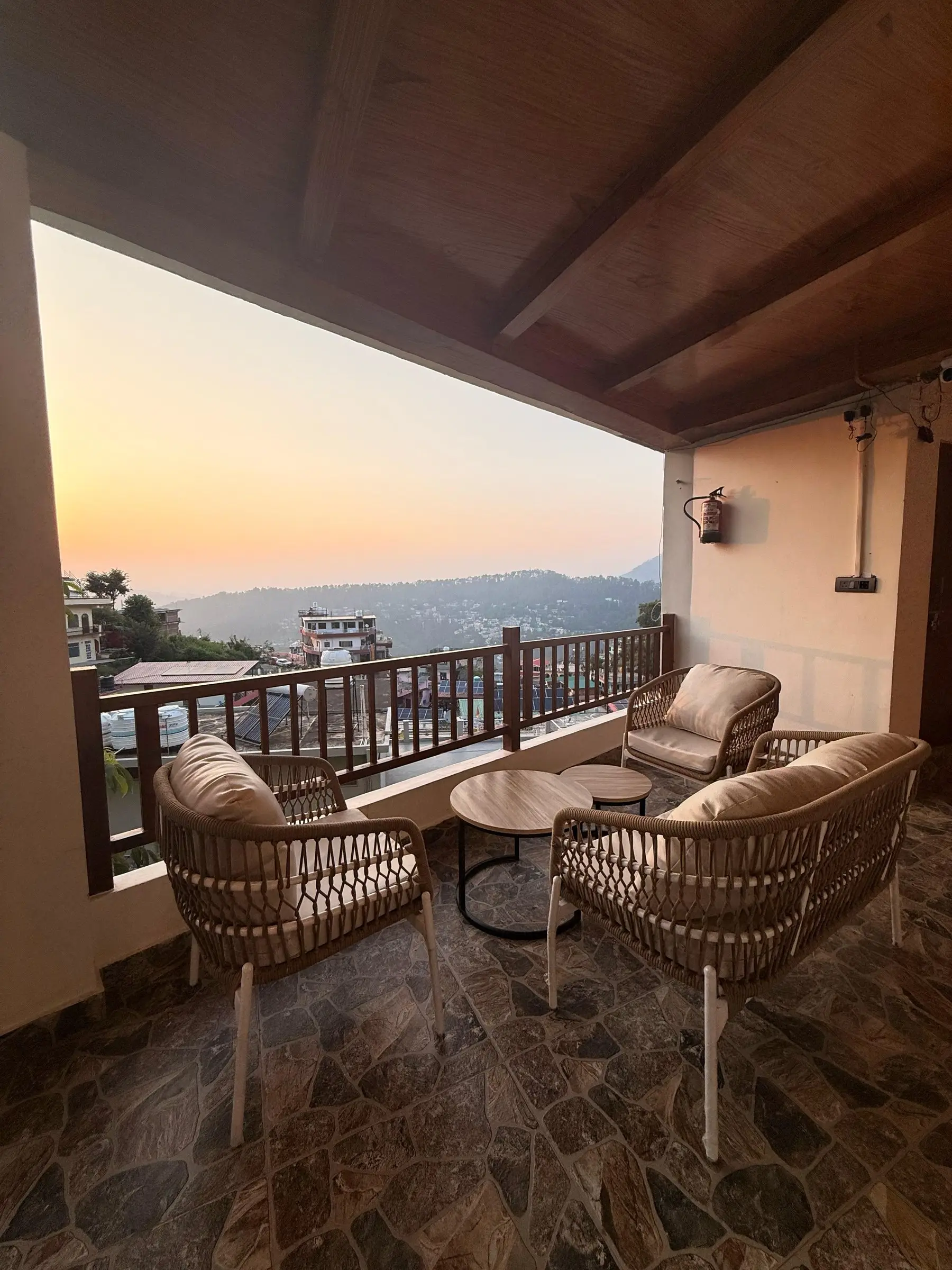 The balcony at sunset, with wicker chairs and hills behind the rooftops