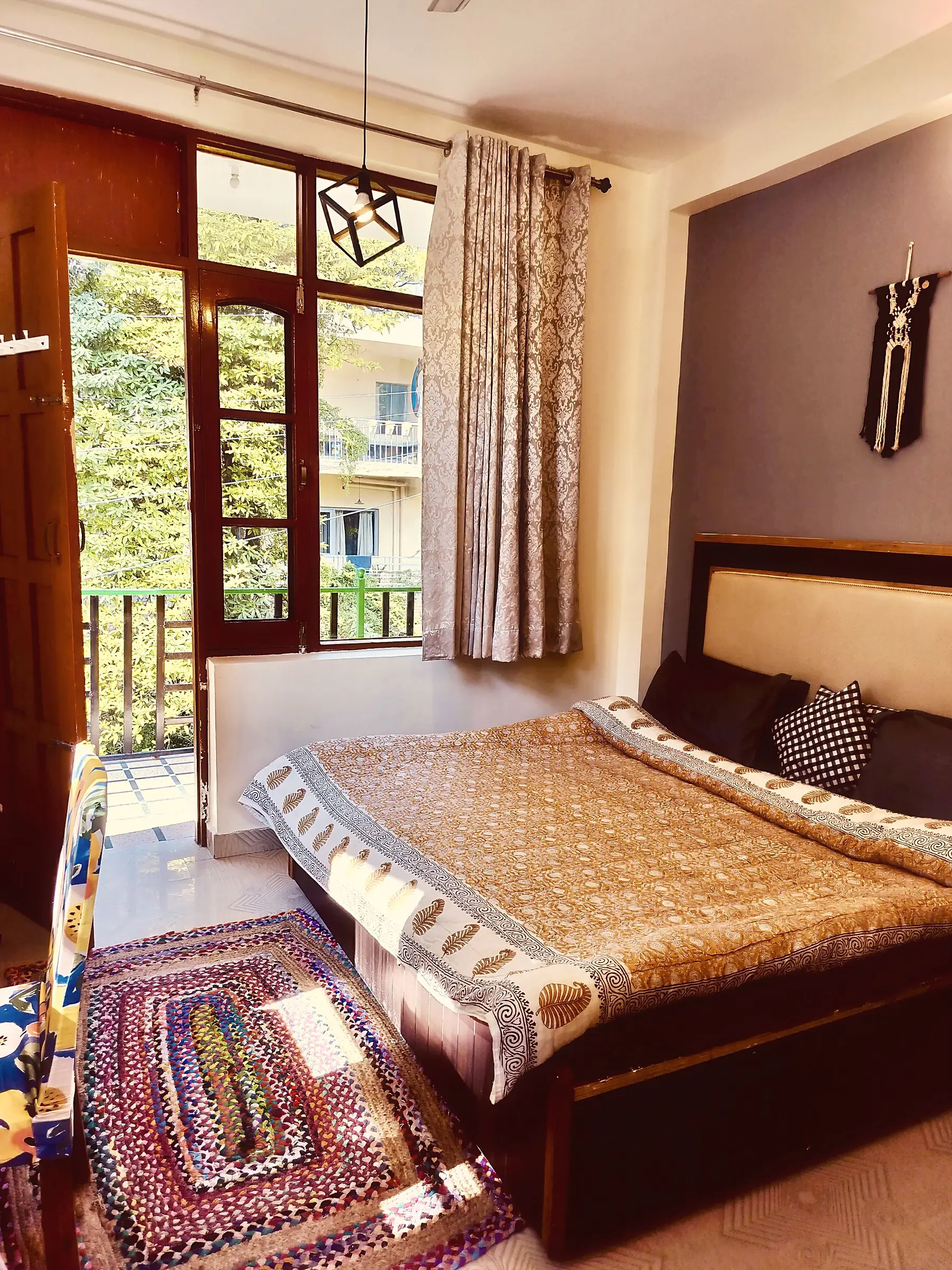 The double bed, with a door open to the balcony and trees