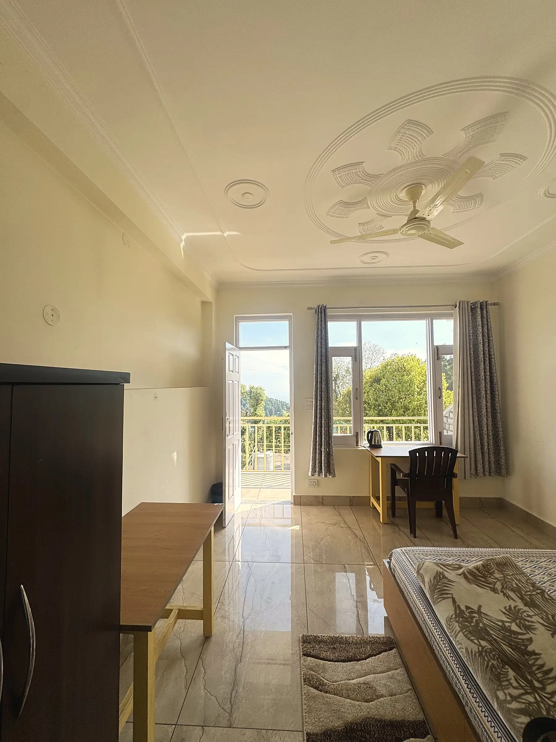 The room from the bed, with the door open onto the balcony
