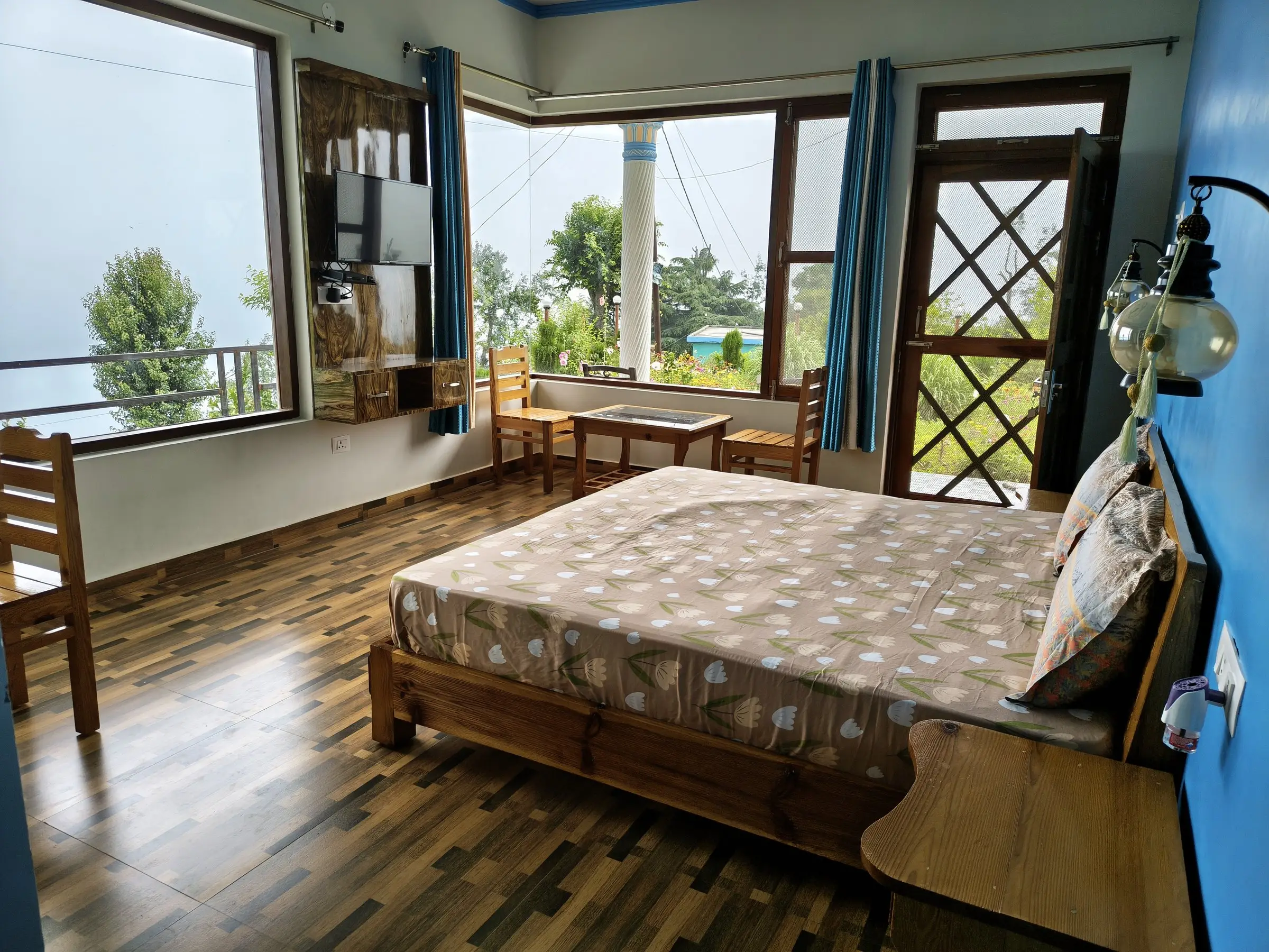 The room with a double bed, a blue wall and a wall-mounted TV