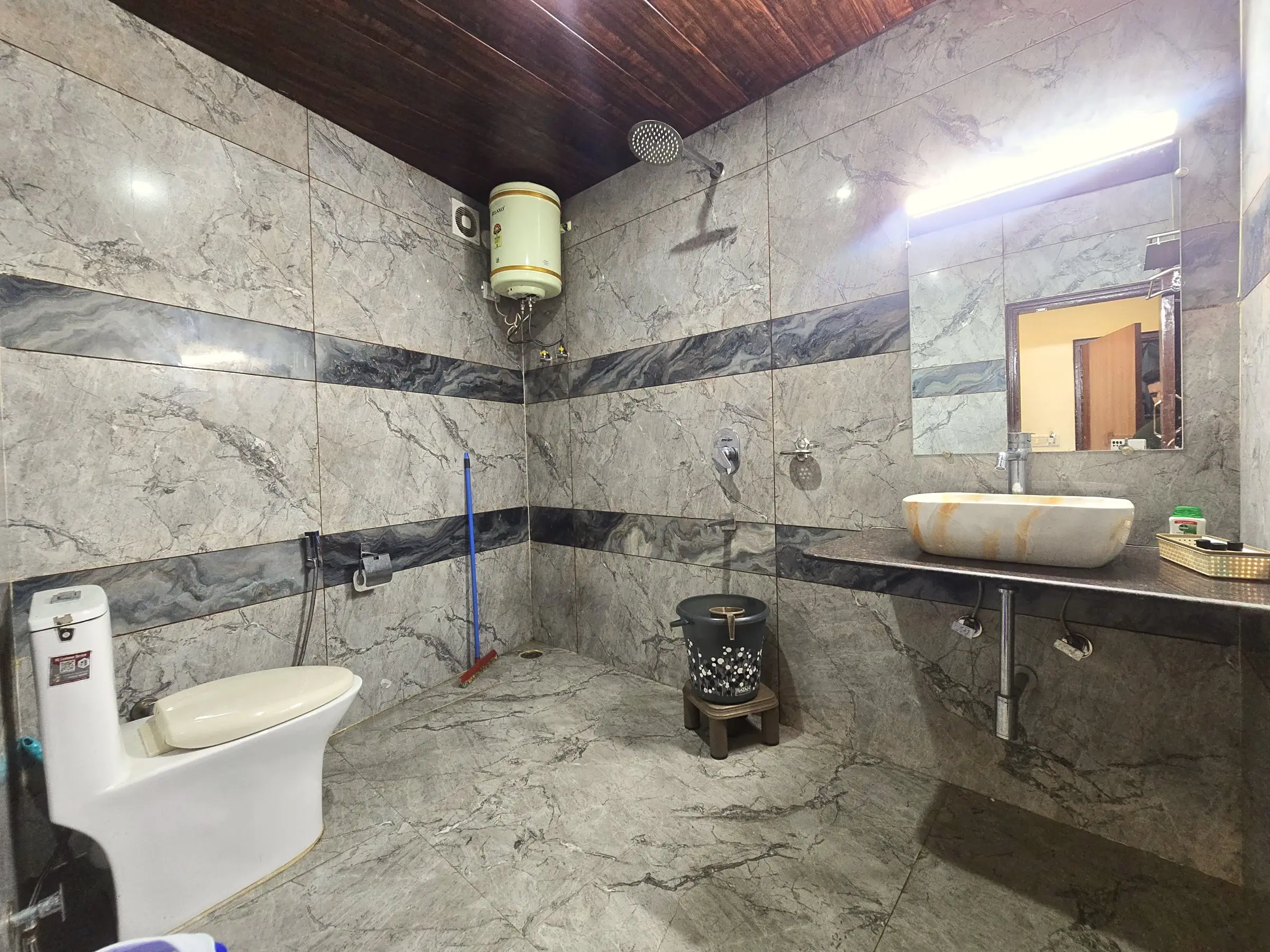 The bathroom, with a rain shower, water heater and basin on a counter