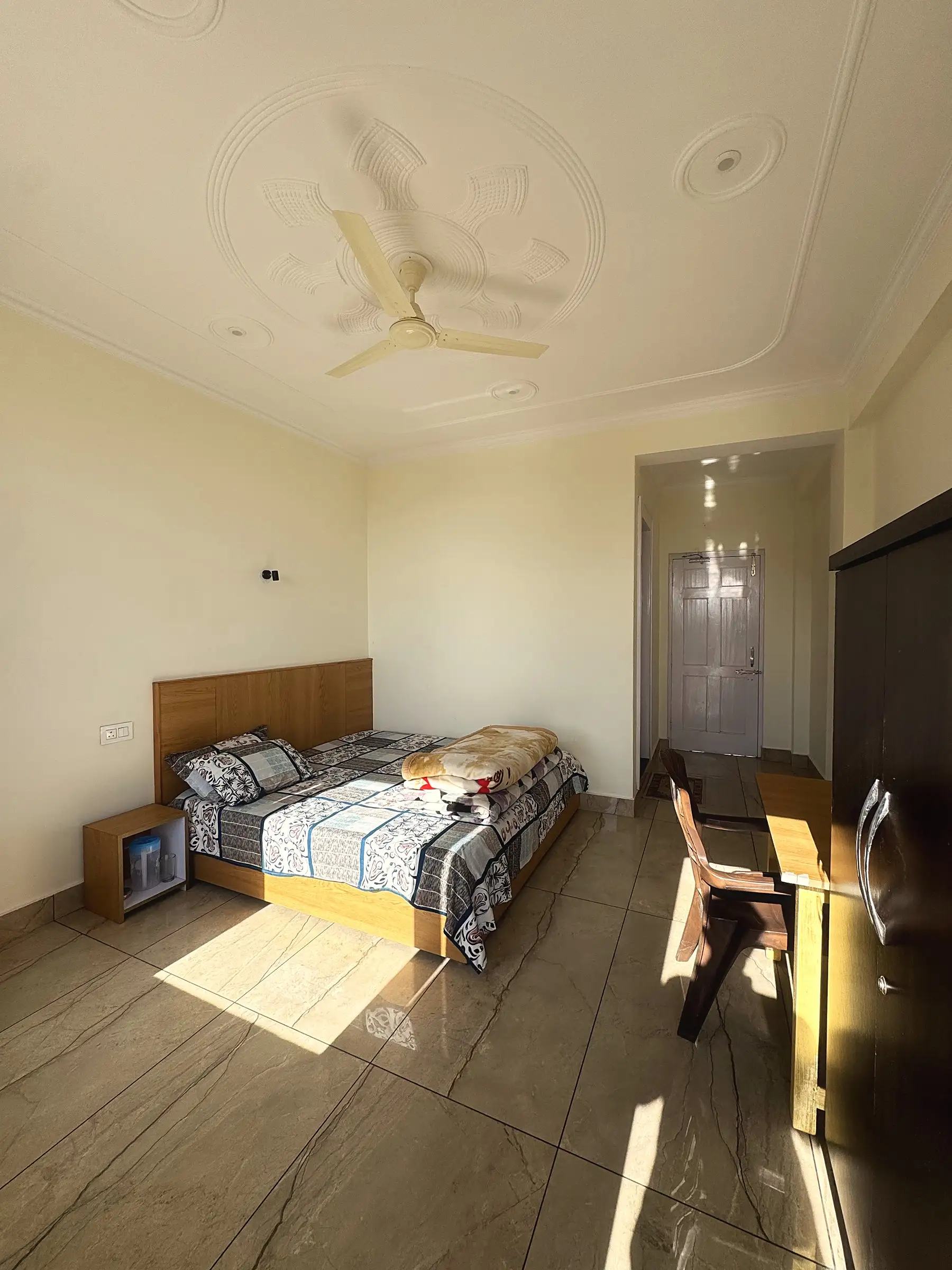 The bed, wardrobe and a second table in afternoon sun