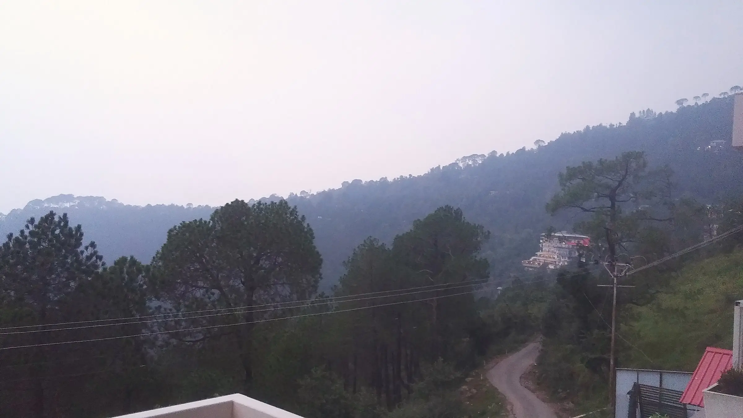 A hazy wooded ridge with a narrow road winding along the slope