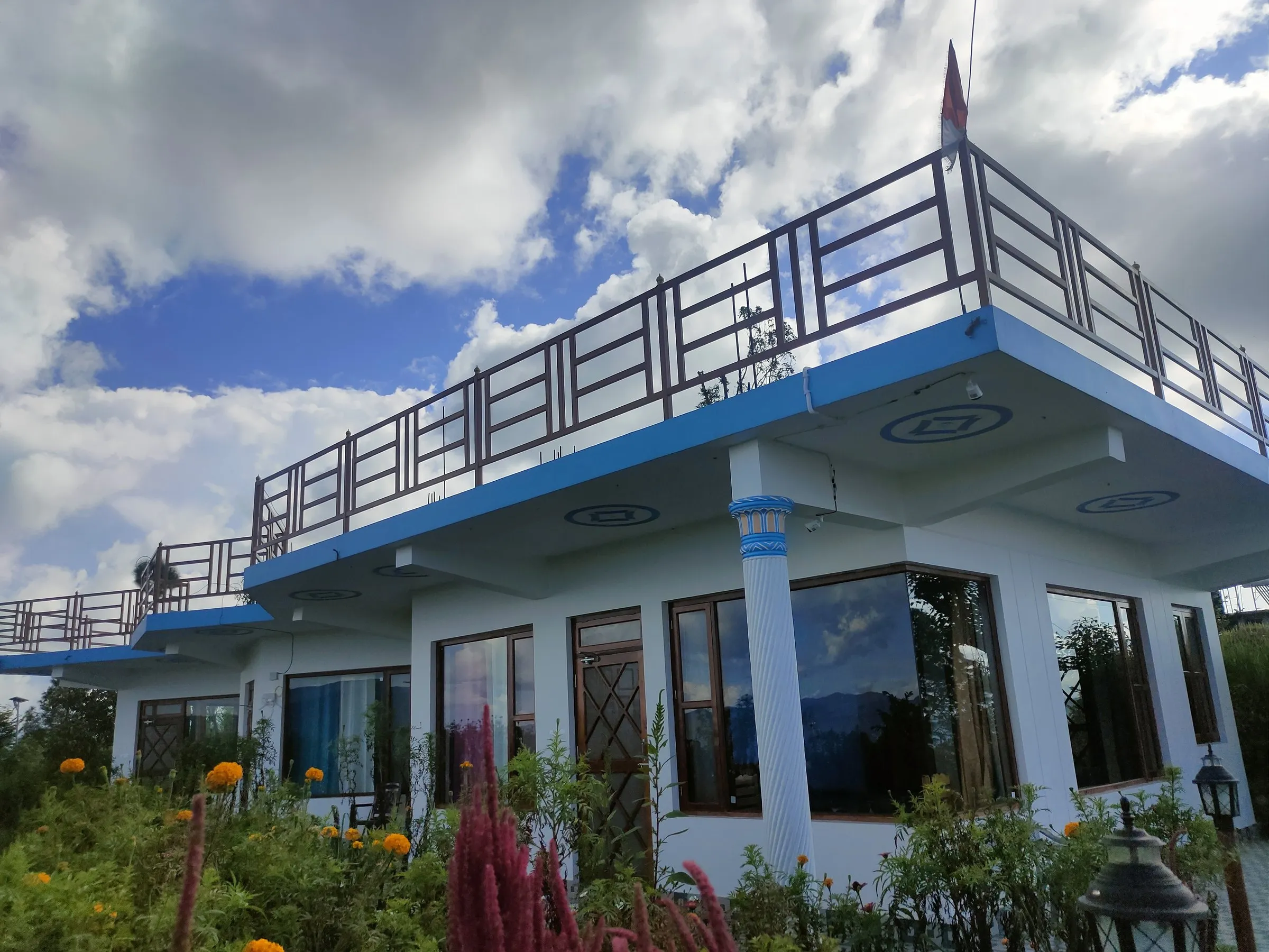 The white building with blue trim, a flat roof and orange flowers