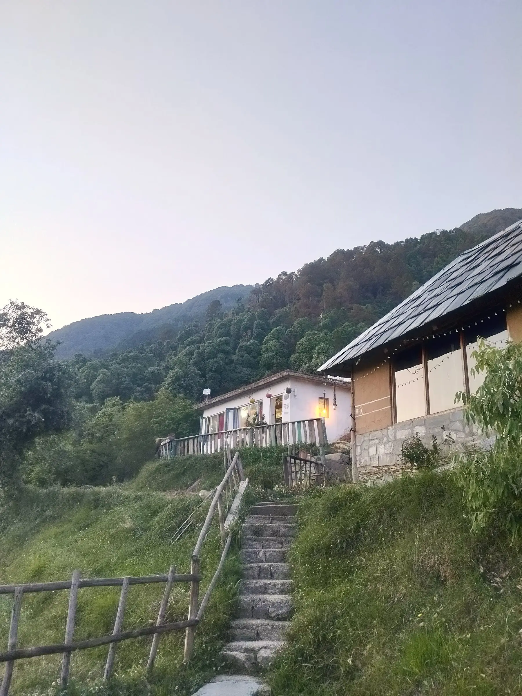 Stone steps climbing to a white building and a slate-roofed one, at dusk