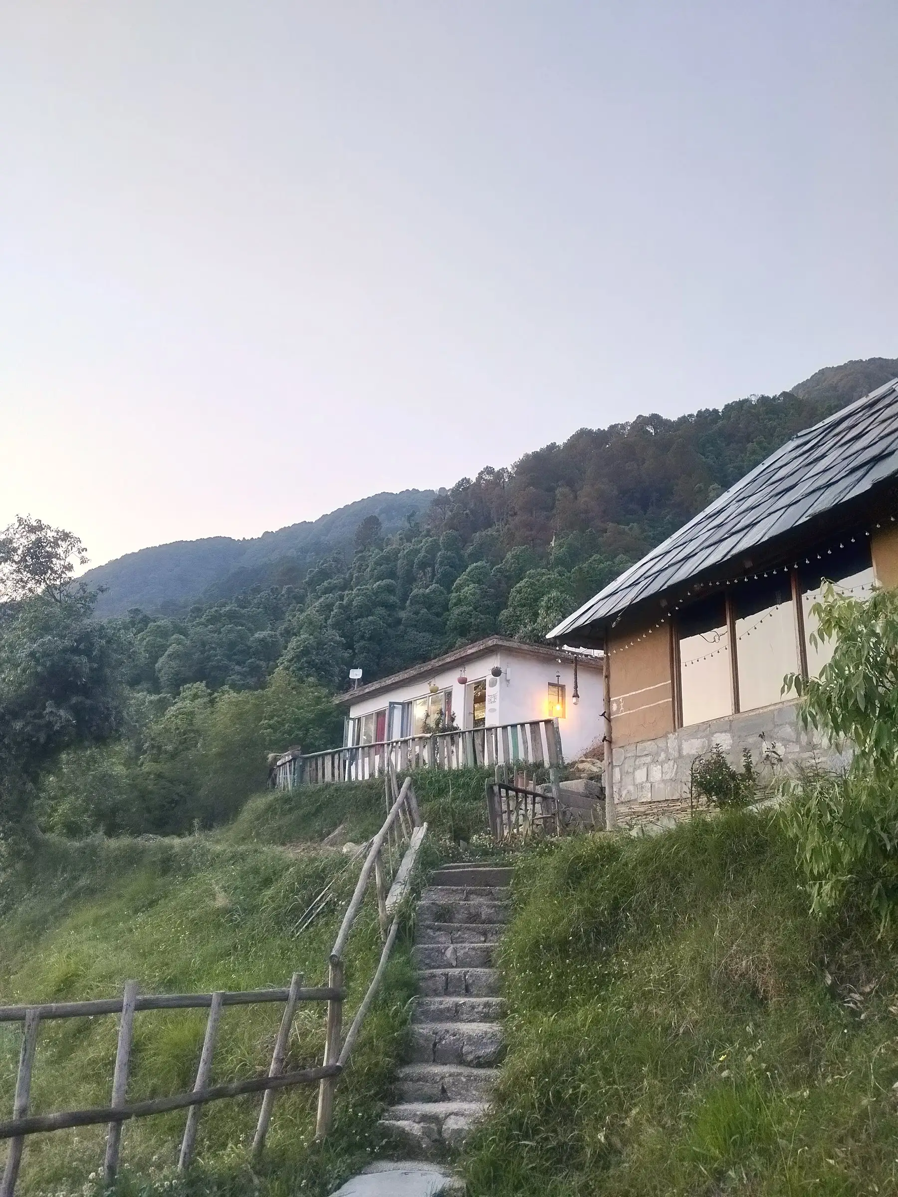 Stone steps climbing to a white building and a slate-roofed one, at dusk