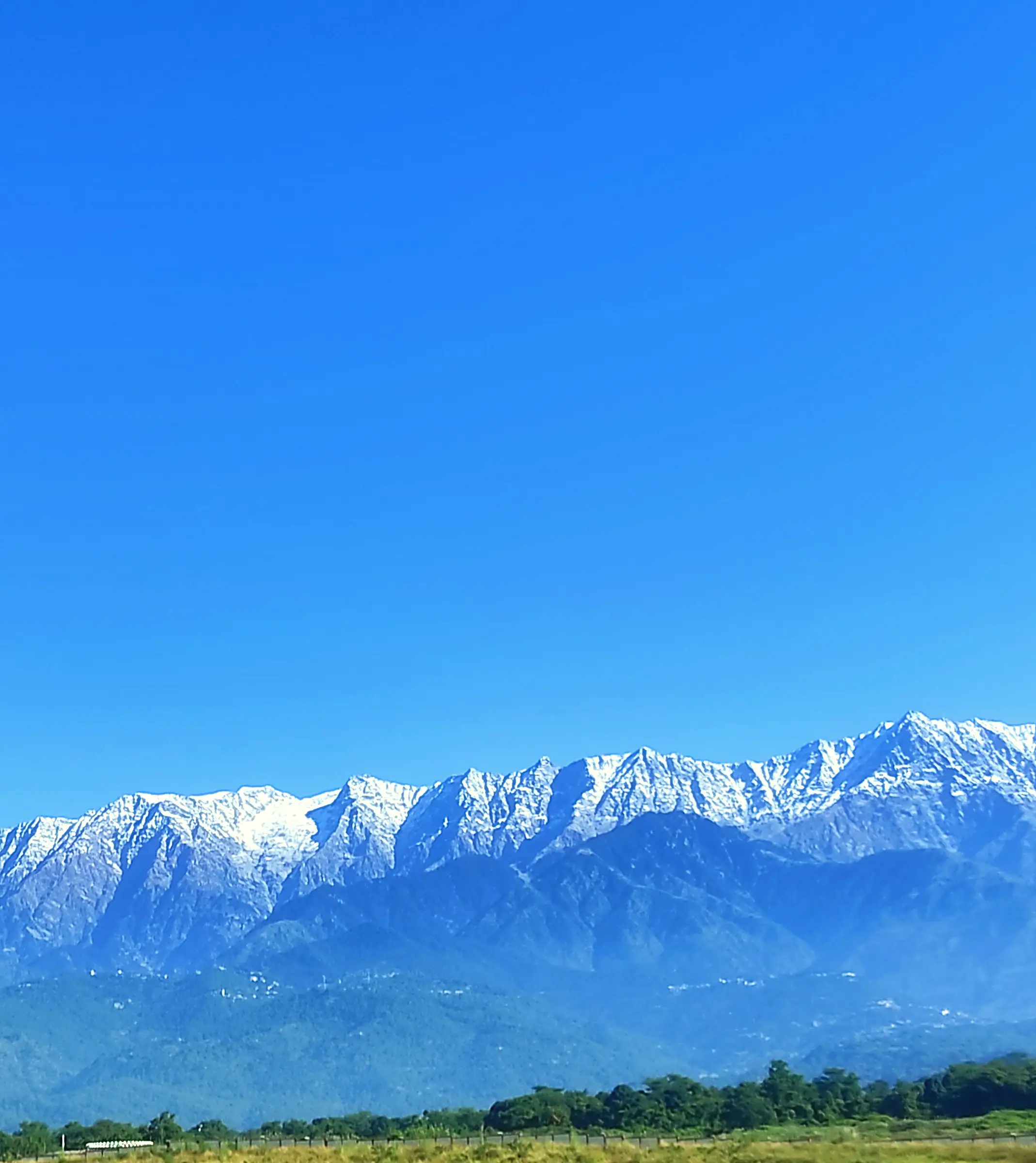 A snow-topped mountain range across a plain under clear sky
