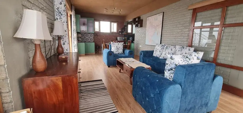 A sitting room with blue sofas, a coffee table and a wooden sideboard