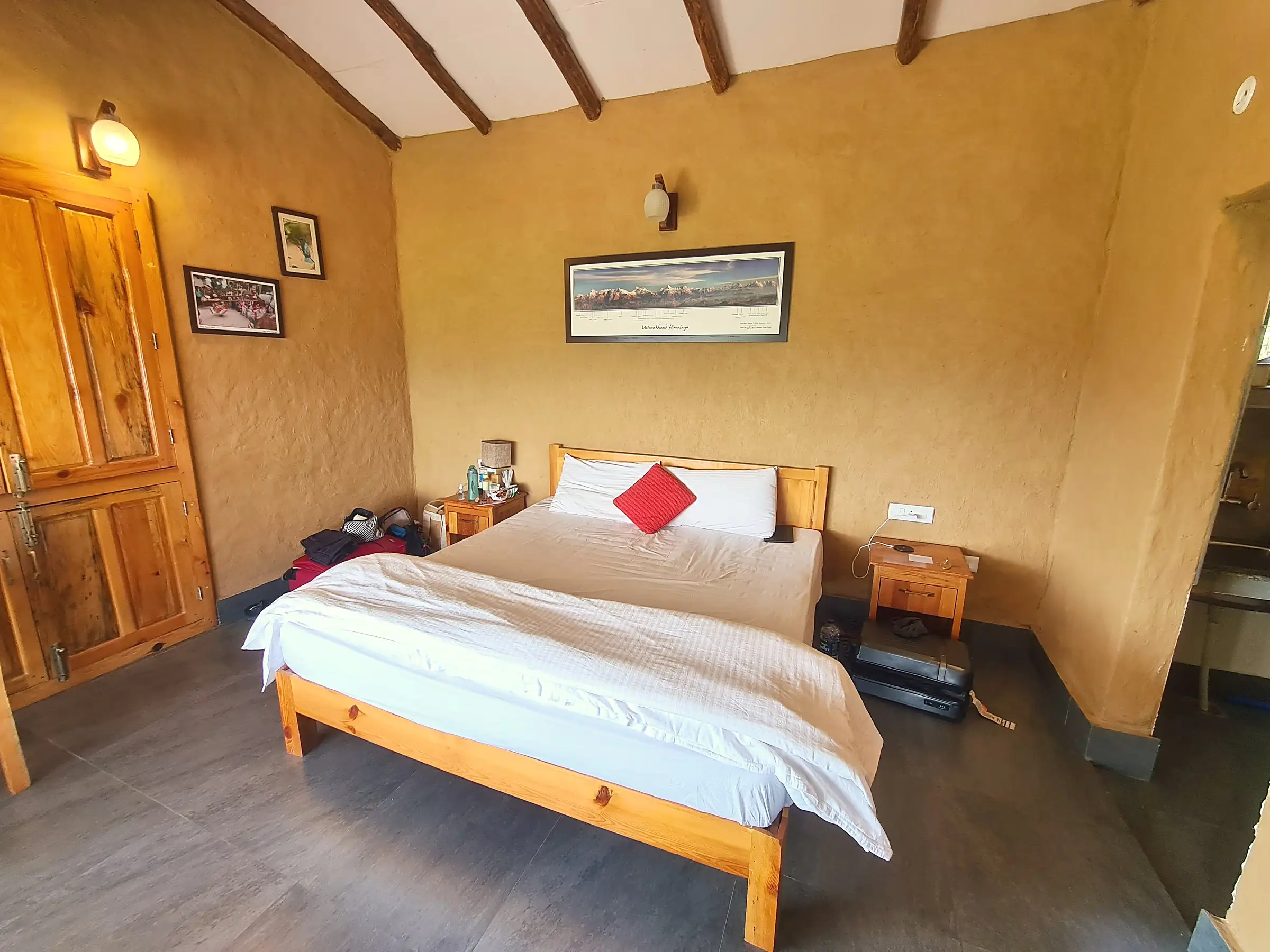 The bed, a wooden wardrobe and a framed panorama of snow peaks