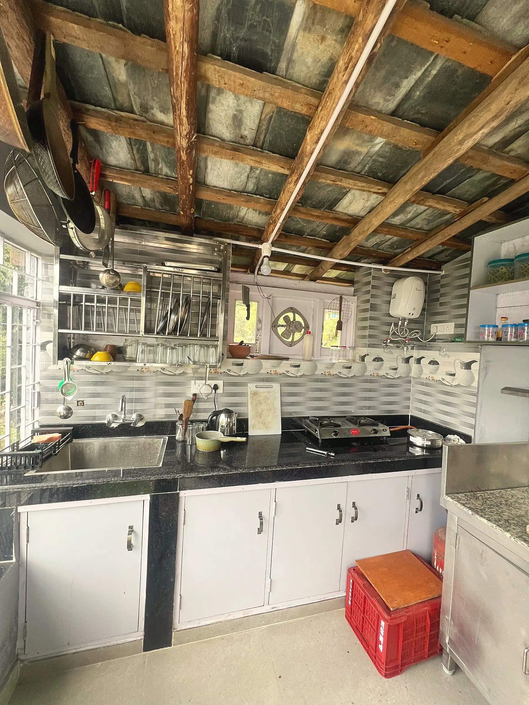The kitchen, with a gas hob, sink and shelves of crockery
