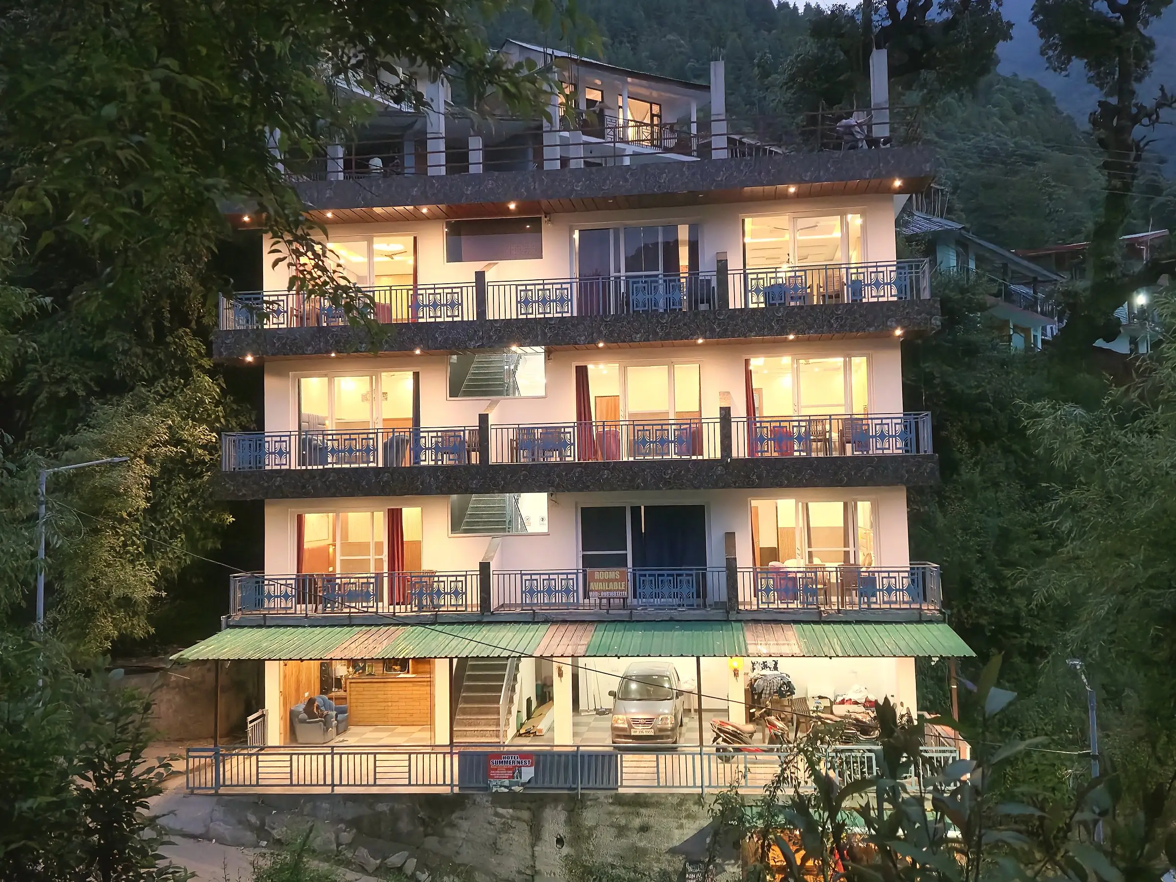 The building lit at night, floors of balconies above a covered entrance