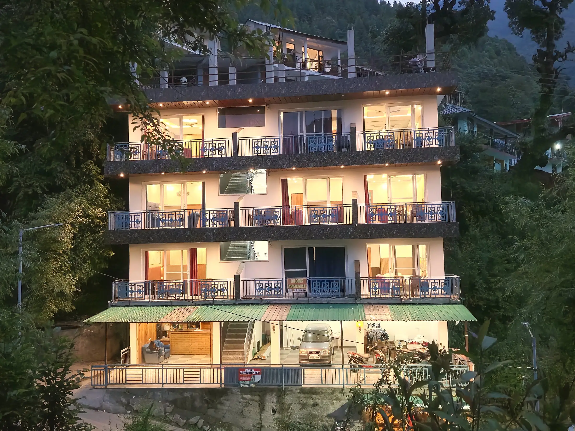 The building lit at night, floors of balconies above a covered entrance