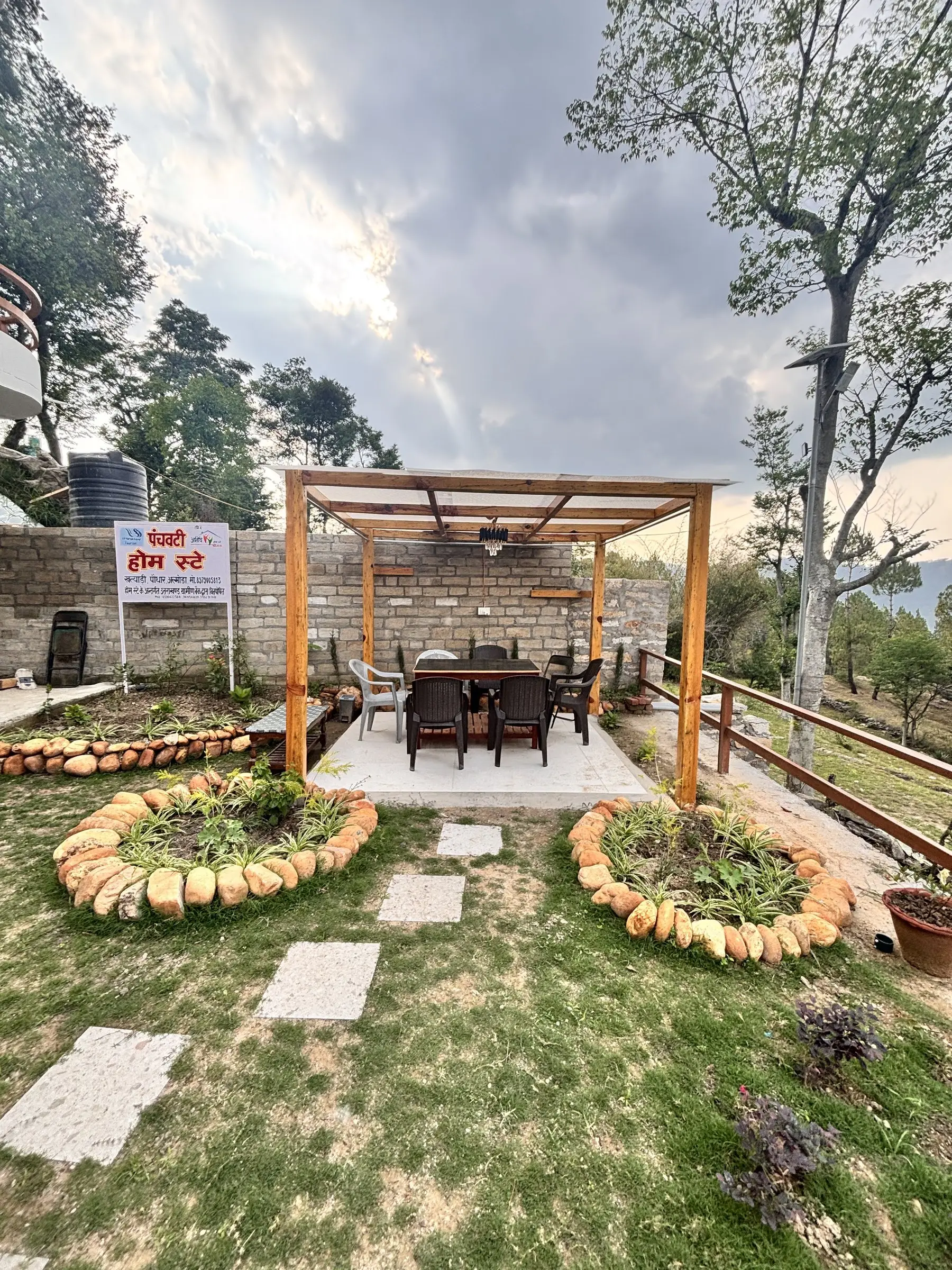 A pergola with a dark table and chairs, set in a lawn