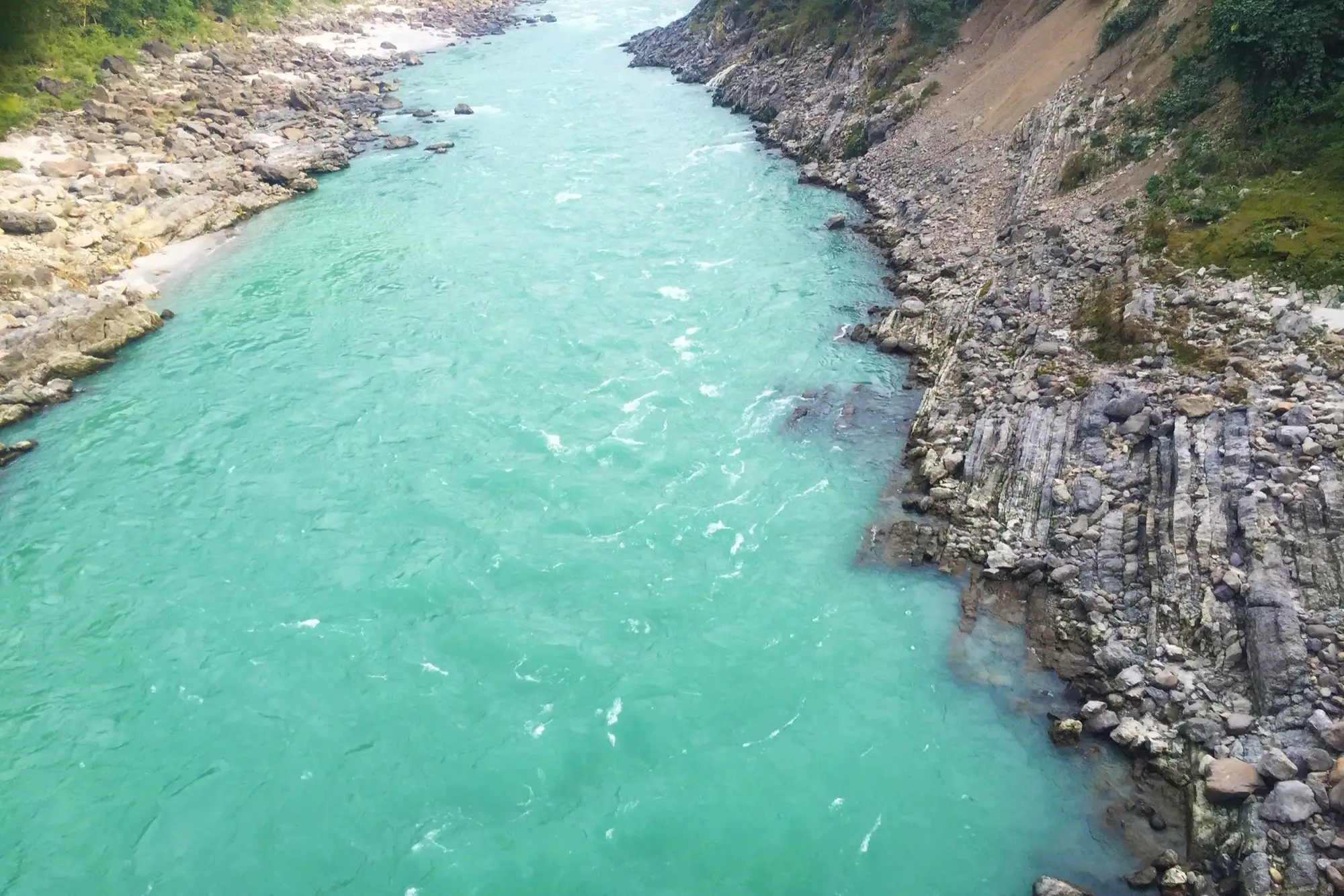 The turquoise Ganga flowing between rocky banks at Rishikesh
