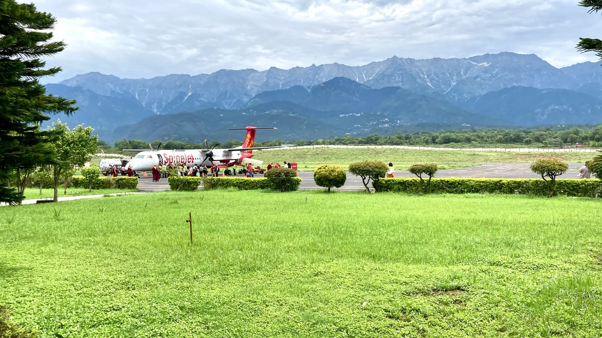 A small aircraft on the apron at Kangra airport, with hills behind