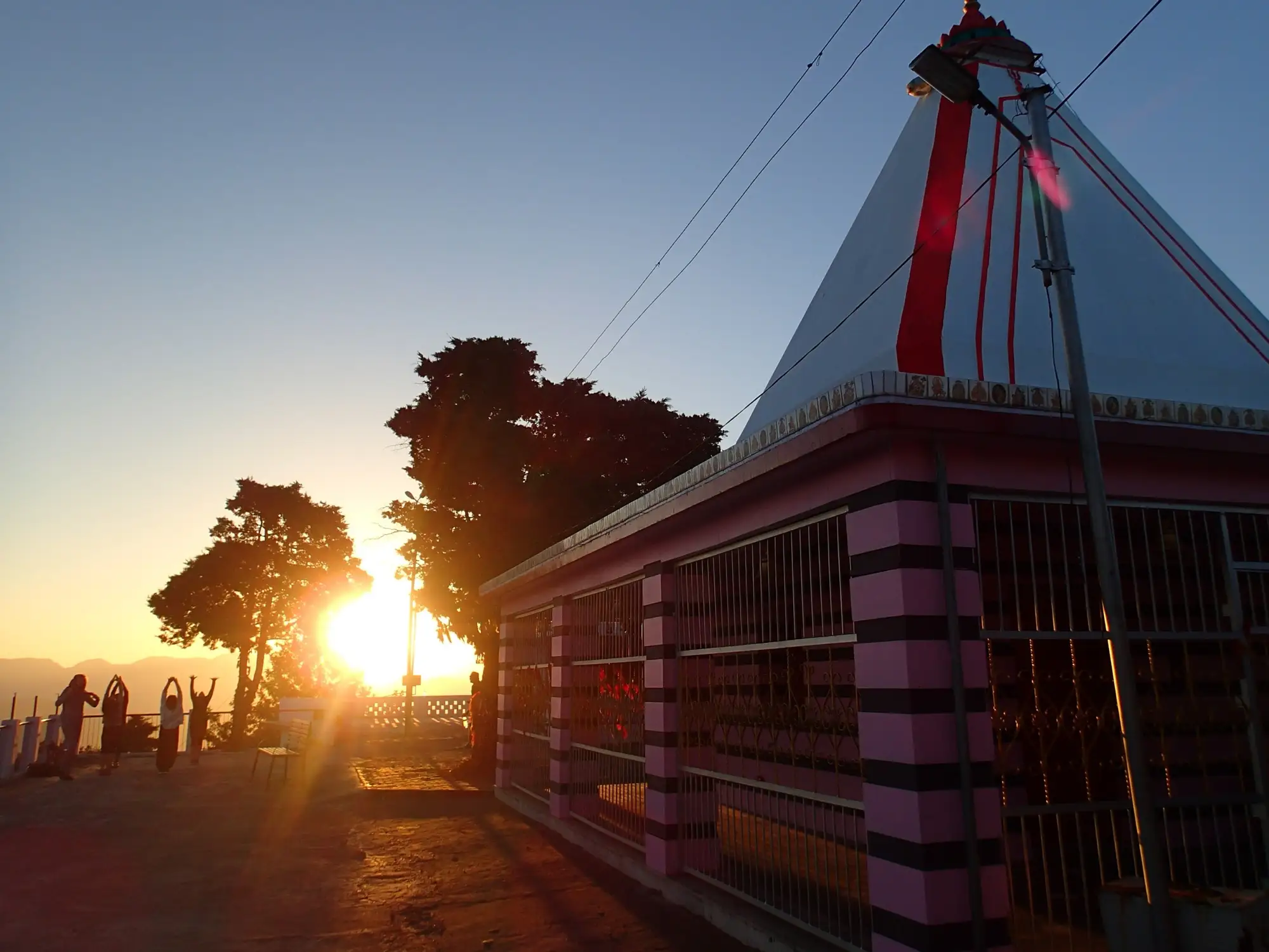 Kunjapuri temple silhouetted against a low sun
