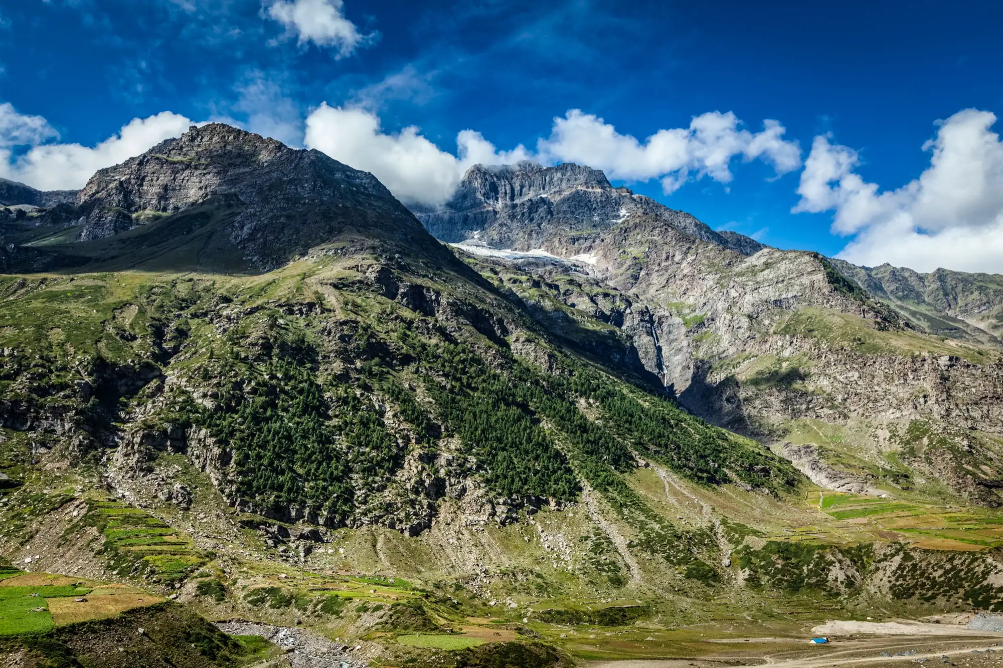 A broad view of the Lahaul valley with green fields below bare mountains