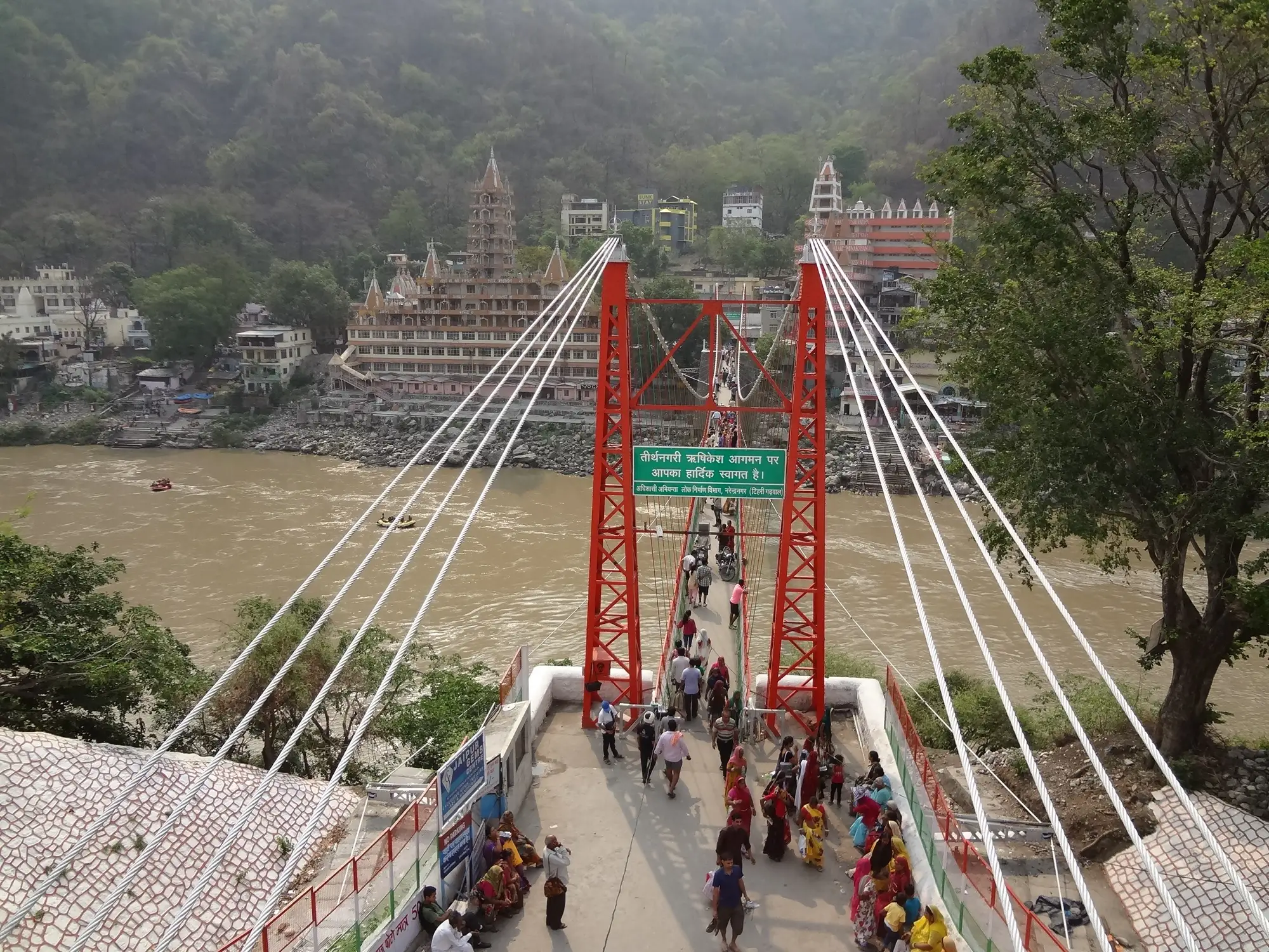 The old Laxman Jhula suspension bridge over the Ganga, with the tiered temple behind it
