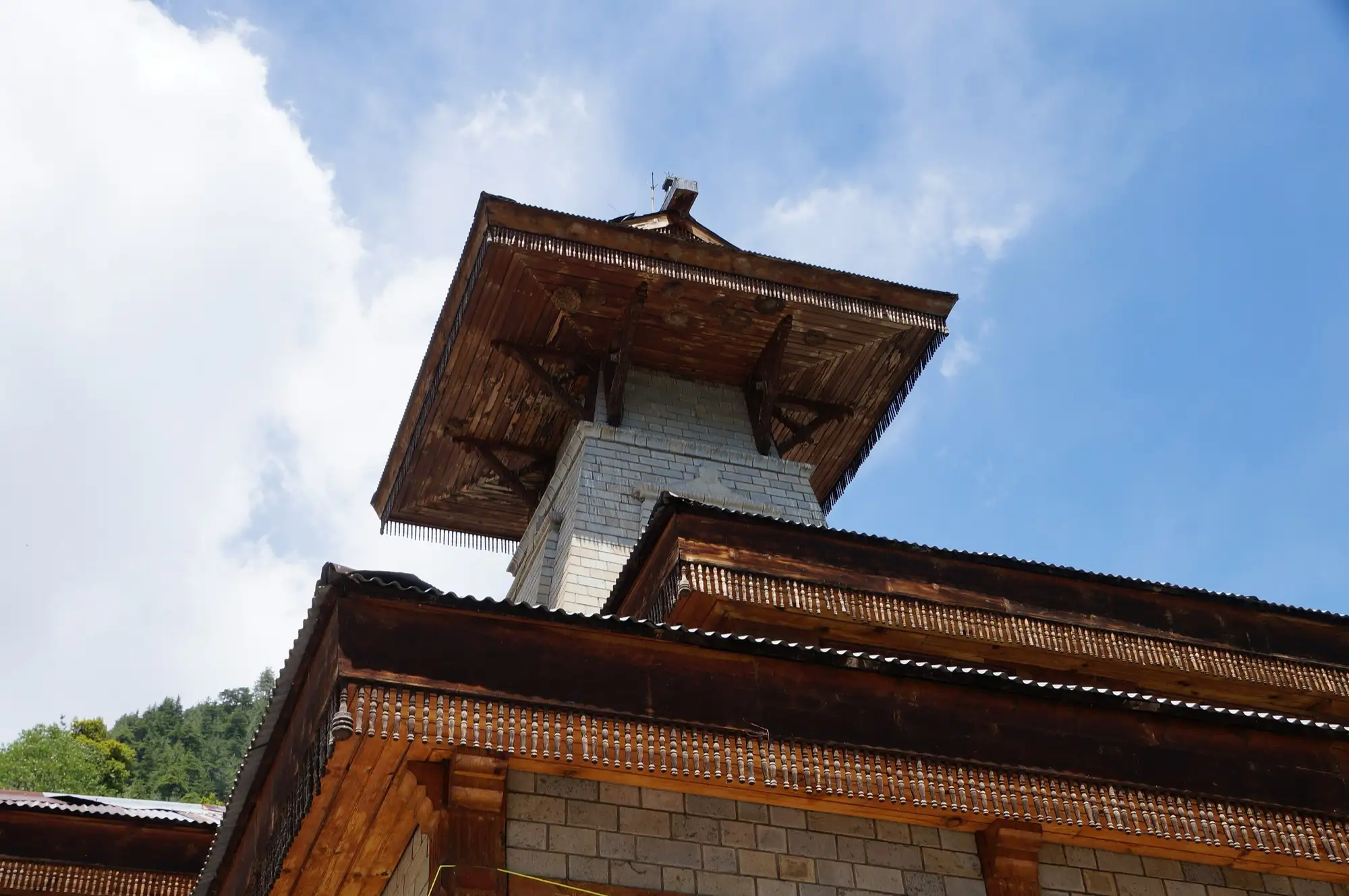 The carved wooden tower of the Manu temple in Old Manali against a blue sky