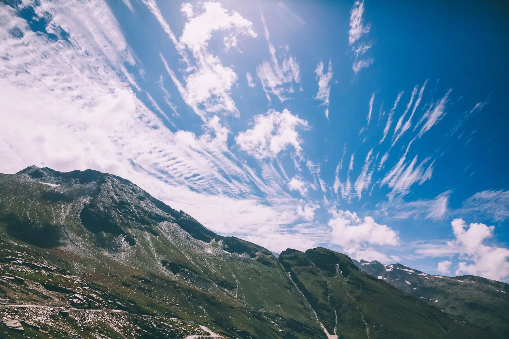 Open green slopes under a streaked blue sky at Rohtang Pass