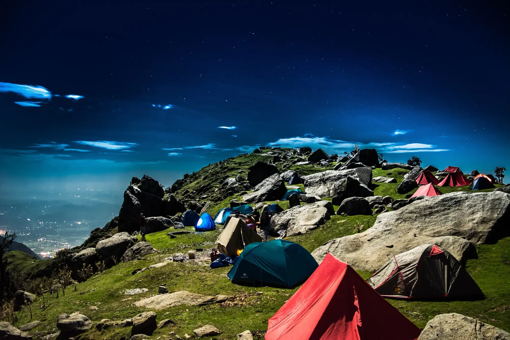 Tents among boulders at the Triund campsite at dusk